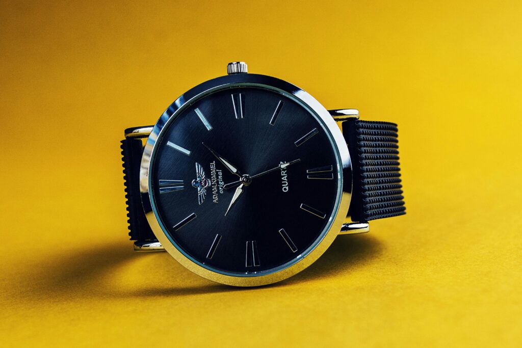 Stylish black analog wristwatch with a black strap on a vibrant yellow background.